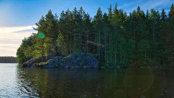 på en sjö i Sverige i smalland. sten i förgrund, blå vatten, himmel, skogar foto