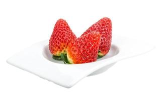 jordgubbe i en skål på vit bakgrund foto