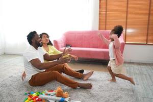 Lycklig afrikansk familj har lekfull tid på Hem, familj kärlek, föräldrar och litet barn inomhus- foto
