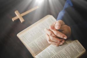 hand vikta i bön till Gud på helig bibel bok i kyrka begrepp för tro, andlighet och religion, kvinna person bön- på helig bibel i morgon. kristen katolik kvinna hand med bibel dyrkan. foto