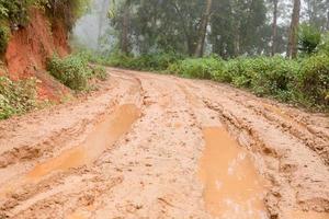 grumlig våt landsbygden väg i chiang maj, nordlig av thailand. Spår spår lera väg i skog natur lantlig landskap. brun lera pöl sätt transport i Land foto