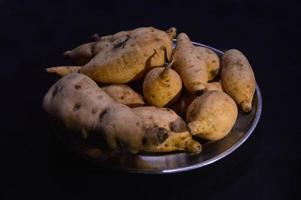 ljuv potatis på en tallrik på en svart bakgrund foto