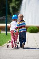 pojke och flicka i parkera inlärning till rida en cykel foto