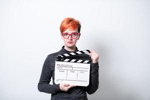 rödhårig kvinna innehav film kläpp på vit bakgrund foto