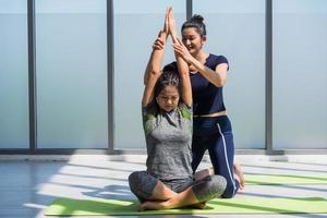 två asiatisk kvinnor håller på med yoga tillsammans på en Gym. foto