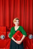 mogna eleganta elegant kvinna med gåva låda på röd bakgrund. fest, mode, firande, anti ålder begrepp. foto
