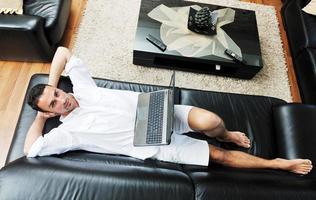 porträtt av en avslappnad ung kille använder sig av bärbar dator på Hem foto