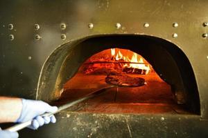 kock med skyddande coronavirus ansikte mask framställning pizza foto