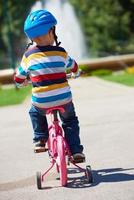 Lycklig pojke inlärning till rida hans först cykel foto