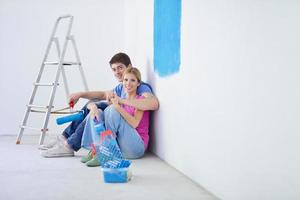 Lycklig ung cople avkopplande efter målning i ny Hem foto