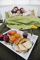 Lycklig ung familj äta frukost i säng foto