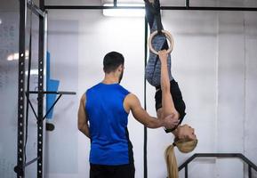 kvinna arbetssätt ut med personlig tränare på gymnastiska ringar foto