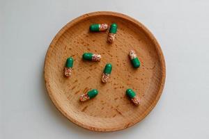 tarmlösliga kapslar med vitaminer på en trä- tallrik. hälsa vård, medicin foto