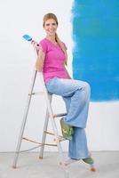 Lycklig leende kvinna målning interiör av hus foto