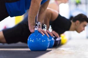 ung idrottare håller på med armhävningar med kettlebells foto