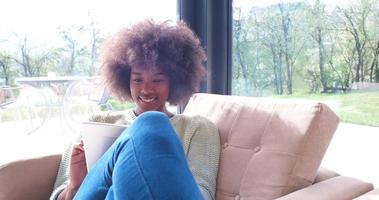 afrikansk amerikan kvinna på Hem använder sig av digital läsplatta foto
