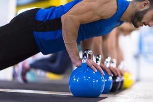 ung idrottare håller på med armhävningar med kettlebells foto