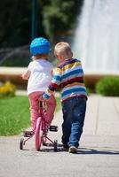 pojke och flicka i parkera inlärning till rida en cykel foto