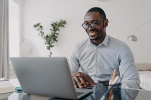 online frilansande distansjobb. afrikansk amerikansk man talar framför kameran på datorn. foto