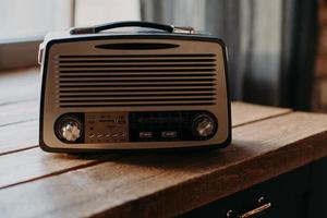 radiosändning av musik. gammal retro radio i ljust rum på träbord. vintage färg. musikalisk bro mellan dåtid och framtid. autentisk retrolook foto