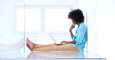 svart kvinnor använder sig av bärbar dator dator på de golv foto