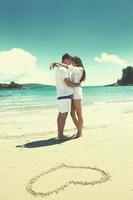 romantisk par i kärlek ha roligt på de strand med hjärta teckning på sand foto