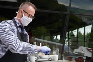 servitör i en medicinsk skyddande mask serverar de kaffe i restaurang foto