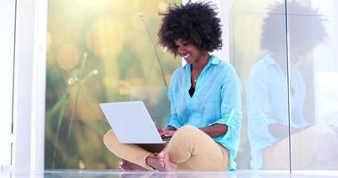 svart kvinnor använder sig av bärbar dator dator på de golv foto