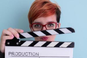 rödhårig kvinna innehav film kläpp på cyan bakgrund foto