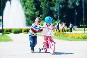 pojke och flicka i parkera inlärning till rida en cykel foto