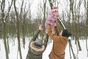 pappa och mamma med en liten dotter i de parkera foto