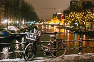 cyklar parkerad längs en bro över de kanaler av amsterdam foto