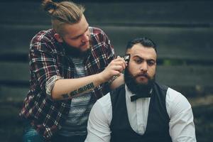 barberare rakar en skäggig man i vintage atmosfär foto
