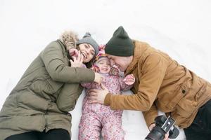 pappa, mamma och liten dotter är liggande på de snö foto