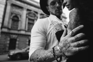 de mannens hand i tatueringar och Smycken omfamnar en flickans midja. foto