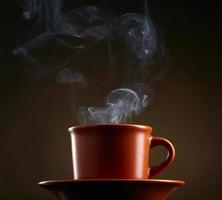 kopp kaffe med rök över mörk bakgrund foto