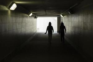 silhuett av människor i de tunnel. de flickor promenad genom ett underjordisk tunnel. foto
