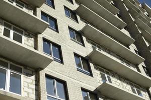 ny byggnad. konstruktion av ett lägenhet byggnad i Moskva. bostads- hus i solljus. infogad plast fönster i de hus. foto
