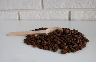 aromatisk kaffe bönor i en trä- sked, kaffe bönor för de produktion av utsökt kaffe. hela kaffe bönor för slipning foto