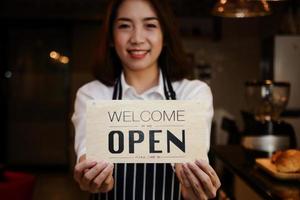 närbild av en skön asiatisk kvinna innehav en tecken till öppen en kaffe affär. konceptuell entreprenörer, sme företag, små mat service restauranger. foto