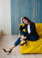 ung kvinna Sammanträde på gul soffa foto