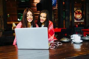 två flickor tittar på något i bärbar dator foto