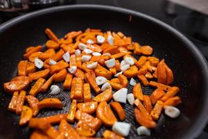 morötter, vitlök i en panorera innan matlagning. stänga veiw foto
