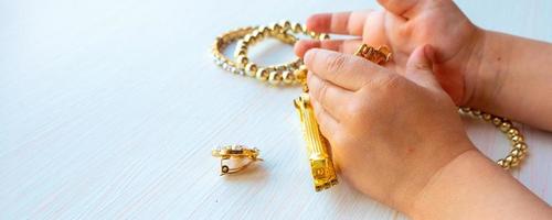 barns händer spela med guld Smycken och bijouteri, på vit bakgrund. begrepp av kvinnor happines foto