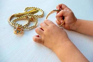 barns händer spela med guld Smycken och bijouteri, på vit bakgrund. begrepp av kvinnor happines foto