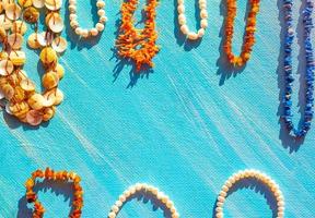 en uppsättning av naturlig Smycken. Plats för de text. korall bärnsten pärla och ben Smycken på en blå bakgrund. topp se. foto