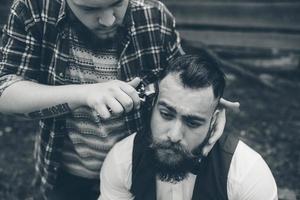 barberare rakar en skäggig man utomhus foto
