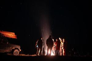 Lycklig vänner har en resten tillsammans runt om lägereld foto