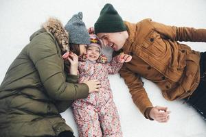 pappa, mamma och liten dotter är liggande på de snö foto