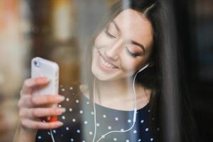 vacker flicka lyssnar på musik i telefon med hörlurar foto